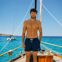 Hombre con bañador Illetes Navy de Beso Beach sobre velero en aguas turquesas del Mediterráneo