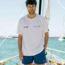 Hombre con camiseta Paradise blanca de Beso Beach a bordo de un velero en el Mediterráneo
